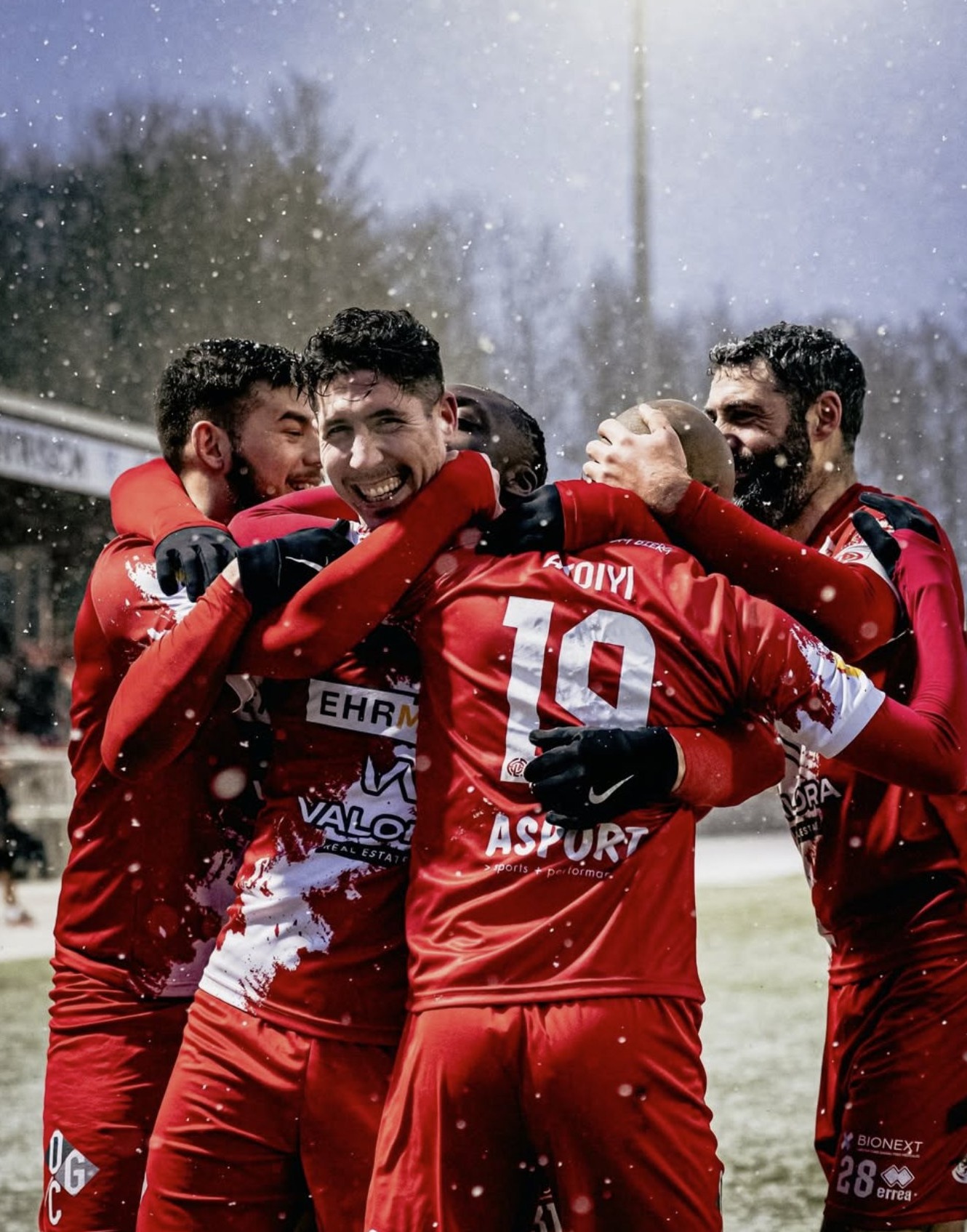 Célébration collective d'une équipe de football en maillot rouge dans la neige