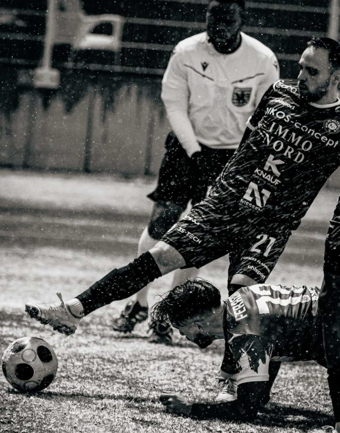 Action de football sous la pluie, frappe à côté de l'arbitre, noir et blanc